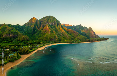 Aerial panoramic image of early morning light just catching the mountains dominating Tunnels beach on Hawaiian island of Kauai with Na Pali mountains