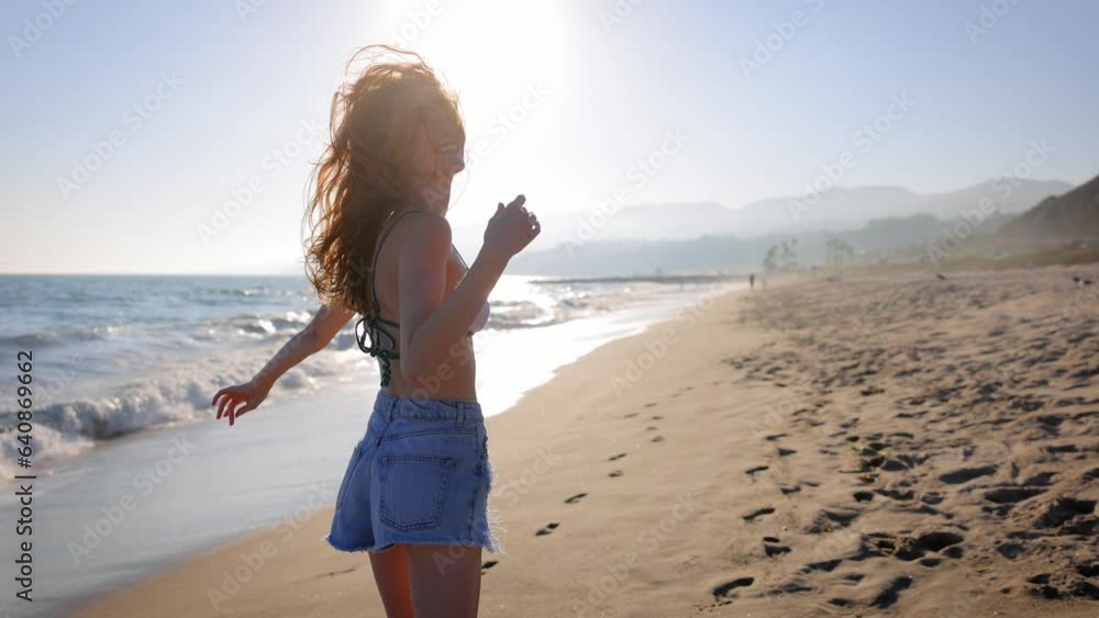 Attractive woman walking on the beach at sunset. Slow Motion.