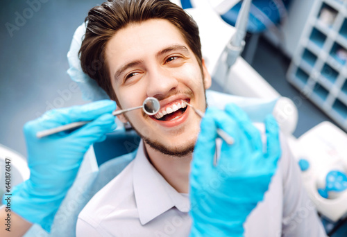 Smiling man in a dental chair during a dental procedure. The patient enjoys dental treatment at a professional dentist. Healthy smile. Dental health.