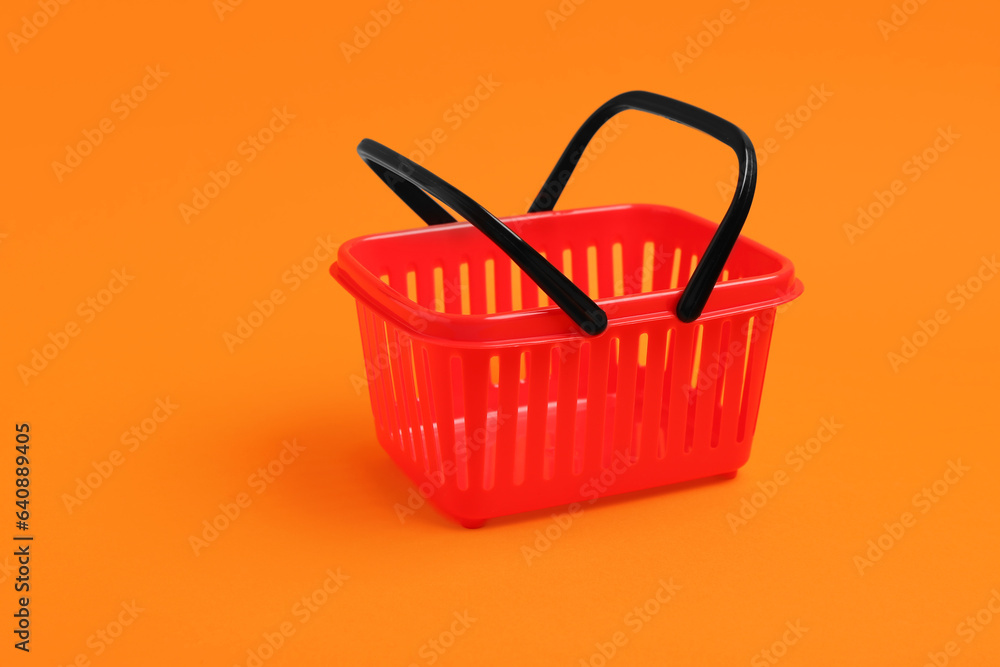 Fototapeta premium Small red shopping basket on orange background