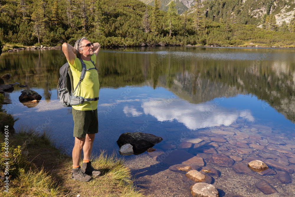 Portrait of an athletic man with a backpack against the background of a mountain lake with a bright reflection