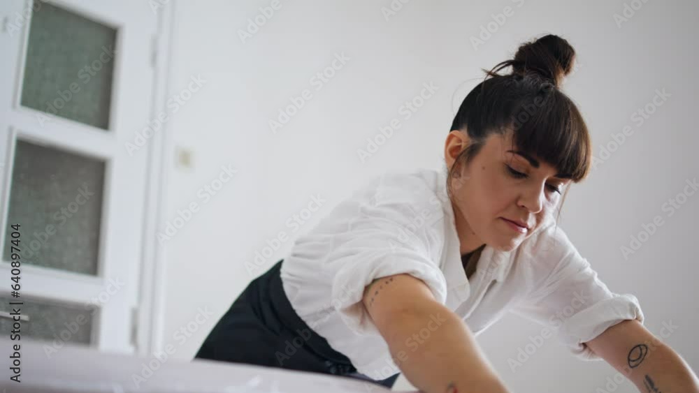 Serious artist using stretching wrap at tattoo studio. Tattooist wrapping couch Serious artist using stretching wrap at tattoo studio. Tattooist wrapping couch