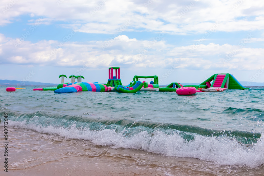 Inflatable bounce castle floating in water. Aqua park for children having fun in water park. Aquapark with attractions in the sea. Popular tourist activity, water sport Inflatable bounce castle floating in water. Aqua park for children having fun in water park. Aquapark with attractions in the sea. Popular tourist activity, water sport
