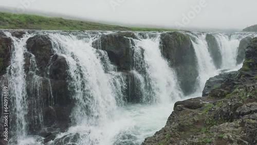 Scenery of Kolugljufur canyon with Kolufossar falls flowing in gorge and wildflower blooming at Iceland photo