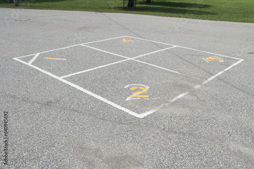 children outdoor four square school yard game printing in white and yellow with one two three four on pavement - two in foreground and four in background