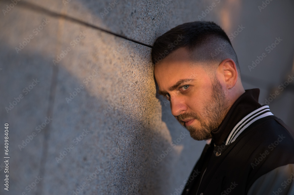 A bearded man in a bomber jacket leaned his forehead against the wall. Problems. A bearded man in a bomber jacket leaned his forehead against the wall. Problems.