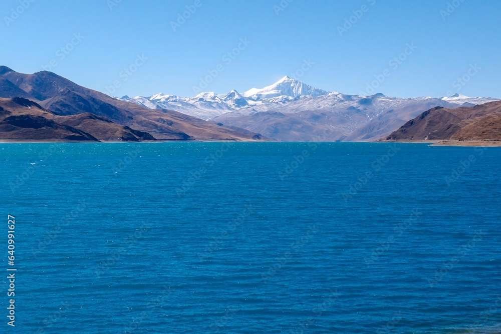 Captured near the tranquil shoreline of Yamdrok Tso lake, this photo showcases the serene beauty of the azure waters and distant snow-capped peaks in the heart of Tibet.