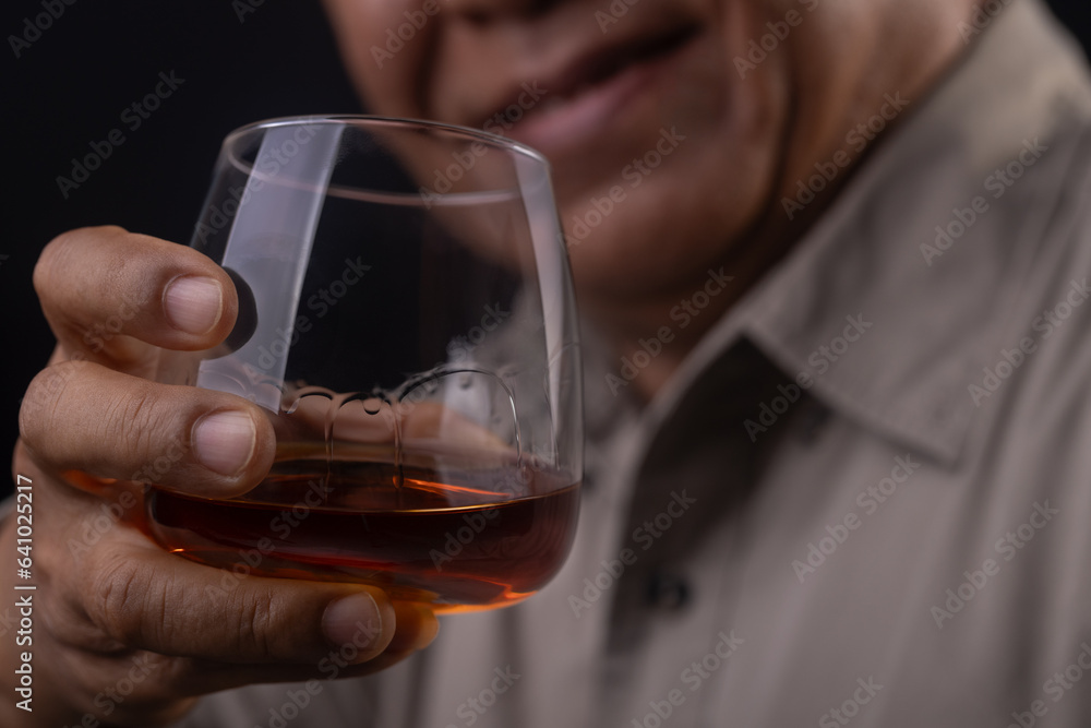 Asian senior man Hand holding glass of whiskey on black background Asian senior man Hand holding glass of whiskey on black background