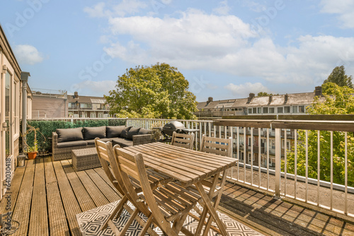 a deck with furniture and trees in the background, taken from an outdoor living area on a blue sky day