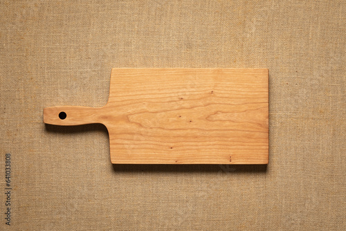 Handmade cherry wood cutting board on burlap. Empty wooden chopping board background.