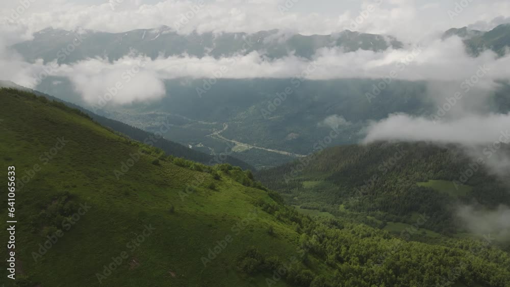 Aerial view of mountains valley with forest in cloudy fog, wide shot Aerial view of mountains valley with forest in cloudy fog, wide shot