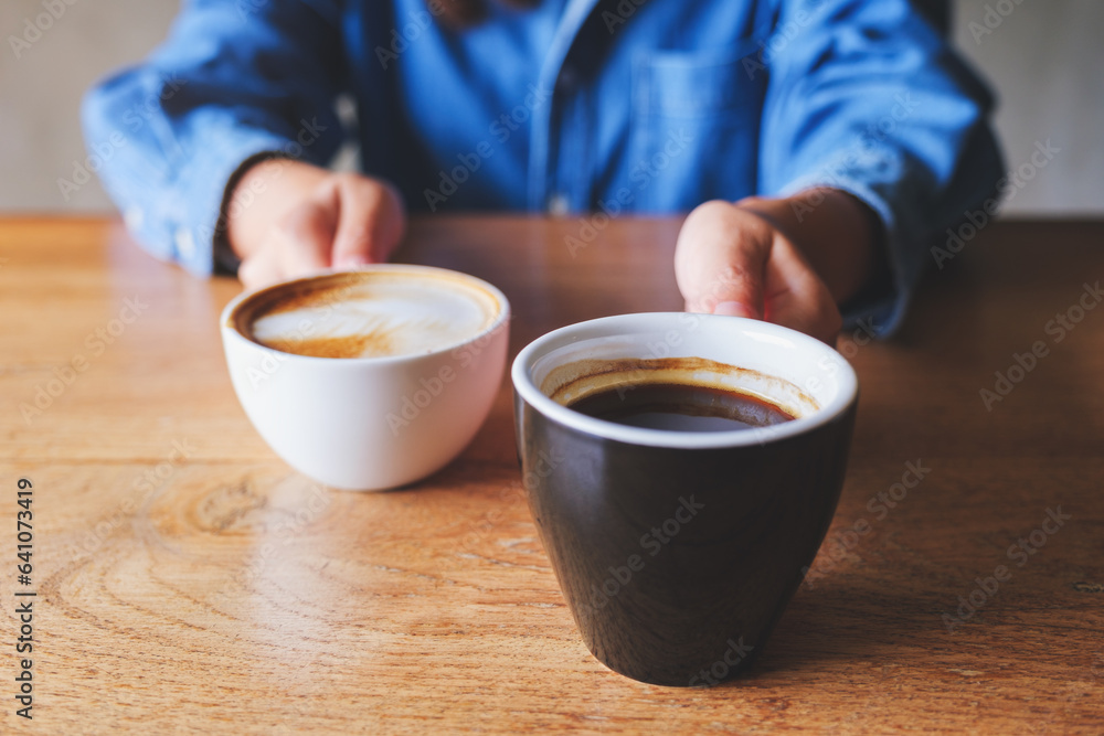 Closeup image of a woman holding and serving two cups of hot coffee Closeup image of a woman holding and serving two cups of hot coffee