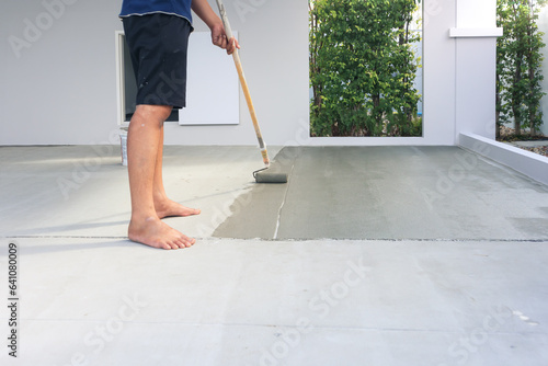 Worker and renovation work. To using roller painting mortar cement or finishing material for repair crack, skim coat or improvement surface of concrete pavement floor or slab for driveway or garage.
 photo