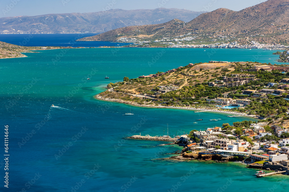 Naklejka premium Turquoise shallow waters and dry, dusty mountains near Elounda and Plaka on the Greek island of Crete in a hot summer