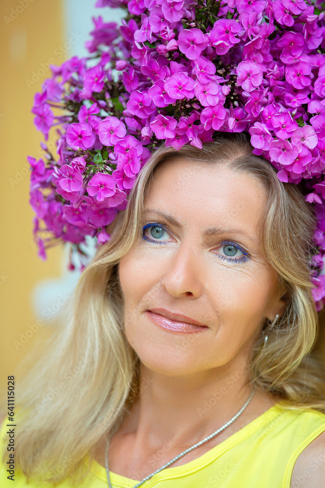 Happy smiling adult woman 50 years old.Aged blue-eyed woman model decorated with purple flowers. Happy smiling adult woman 50 years old.Aged blue-eyed woman model decorated with purple flowers.