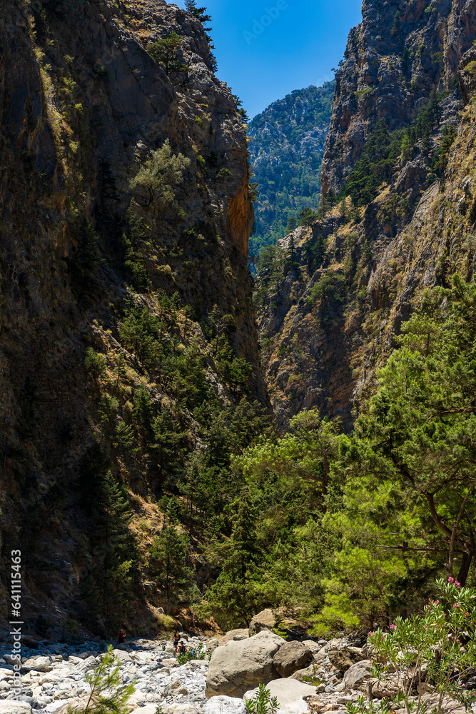 Hikers in a deep gorge surrounded by spectacular cliffs during a hot summer