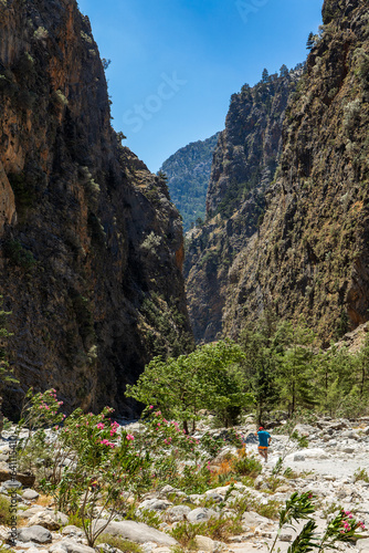 Hikers in a narrow gorge with huge, towering cliffs either side (Samaria Gorge, Greece)
