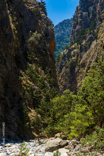 Hikers in a deep gorge surrounded by spectacular cliffs during a hot summer