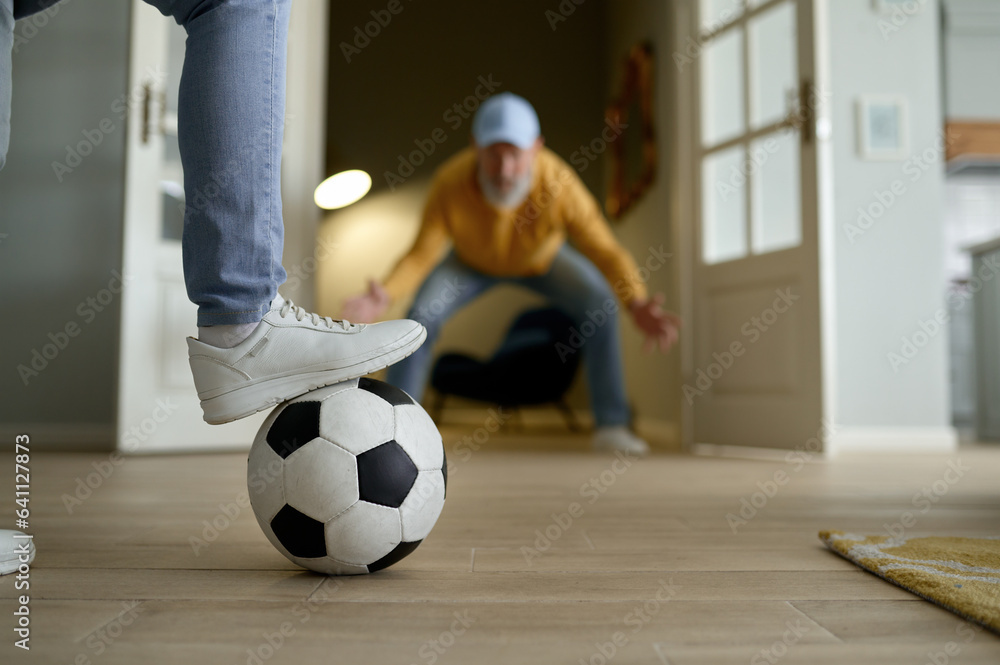 Fototapeta premium Happy couple of retiree playing football, selective focus of foot on ball
