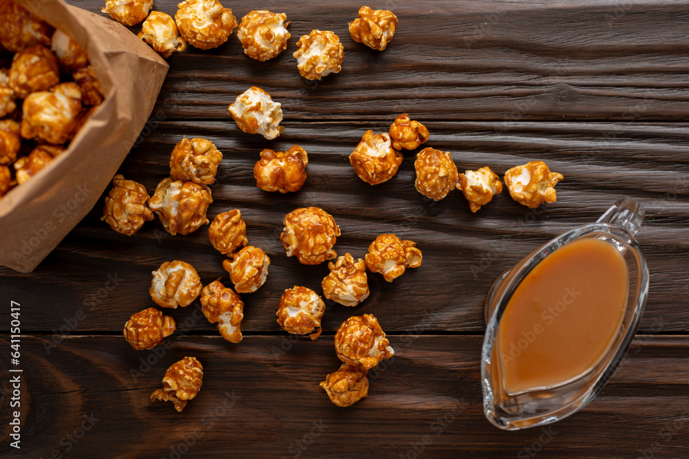 Caramelized popcorn in paper bag on wooden kitchen table flat lay