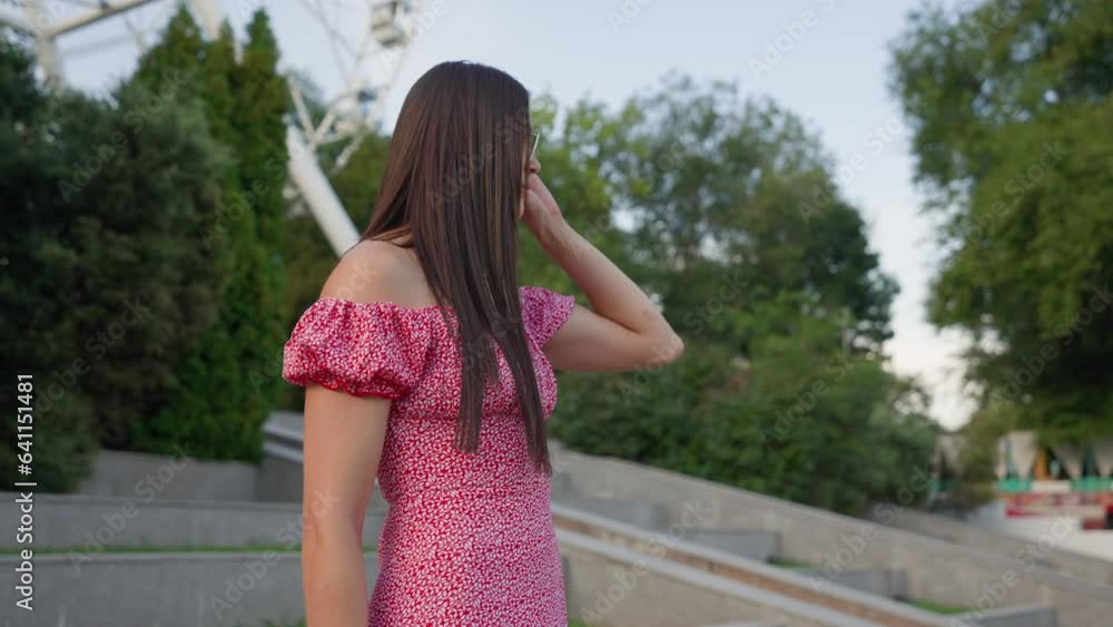 Attractive Brunette Woman in a Pink Dress and Glasses Smiles and Walks in the City Center. Happy Girl Enjoys a Walk in the City. Slow Motion. Attractive Brunette Woman in a Pink Dress and Glasses Smiles and Walks in the City Center. Happy Girl Enjoys a Walk in the City. Slow Motion.