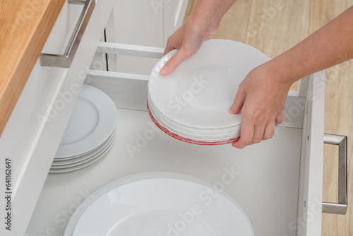 Stos białych talerzy wkładany do szuflady 