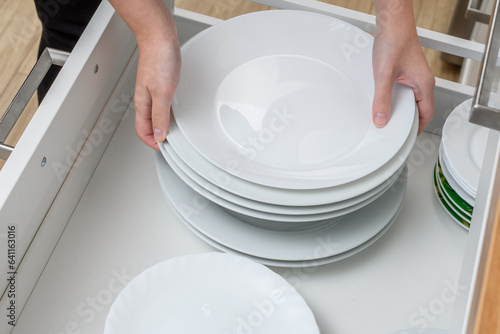Stos białych talerzy obiadowych trzymany w dłoniach 