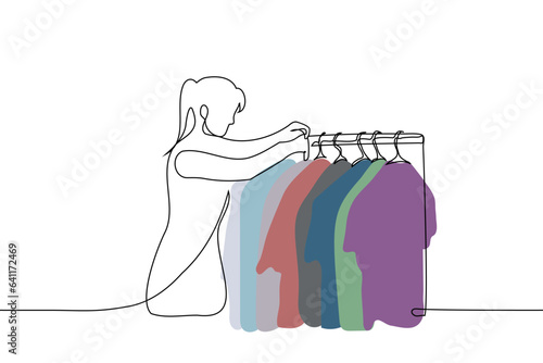 woman standing over clothes hanger - one line art vector. concept consultant in a clothing store, a girl chooses clothes in her wardrobe, a stylist selects an look