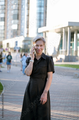 Business Woman With Phone Near Office. Portrait Of Beautiful senior Female In Fashion Office Clothes Talking On Phone While Standing Outdoors. Phone Communication. © lelechka