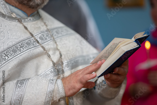 The hands of an Orthodox priest in a cassock hold a bible.