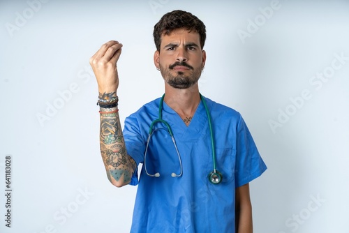 young caucasian doctor man wearing blue medical uniform angry gesturing typical italian gesture with hand, looking to camera © Roquillo