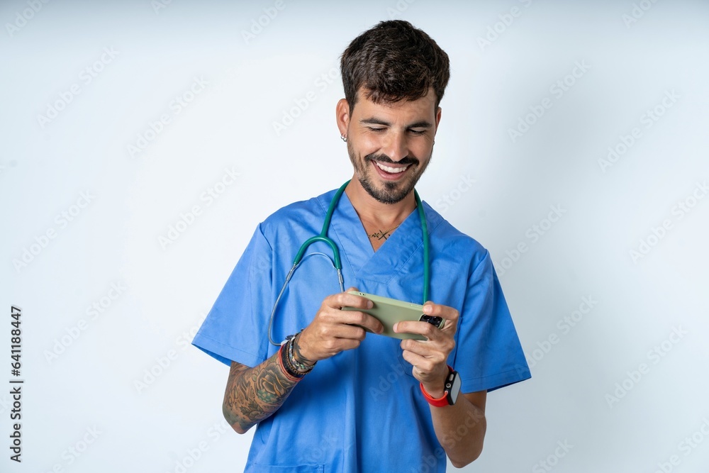 young caucasian doctor man wearing blue medical uniform holding in hands cell playing video games or chatting young caucasian doctor man wearing blue medical uniform holding in hands cell playing video games or chatting
