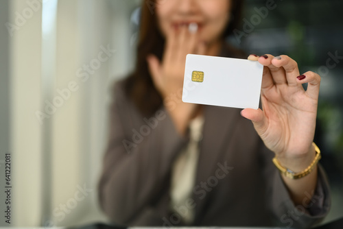 Surprised young woman showing credit card. Select focus on hand. Electronic money, contactless payment concept