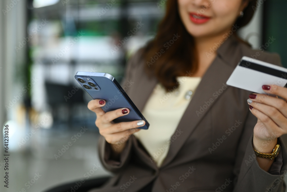 Select focused on woman hand holding credit card and using smartphone. E-commerce, banking service and shopping online Select focused on woman hand holding credit card and using smartphone. E-commerce, banking service and shopping online