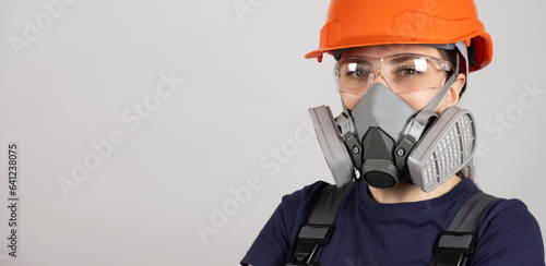 A woman wears a protective respirator with dust and gas filters on a white background.