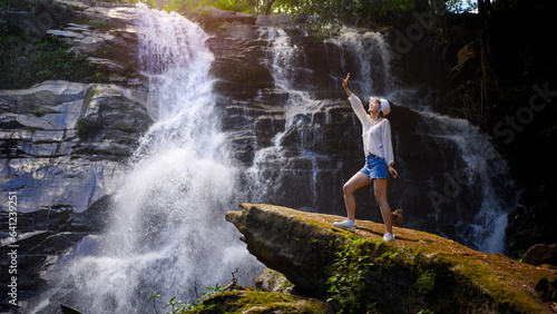 asian woman traveller relaxing in deep tropical jungle waterfall 