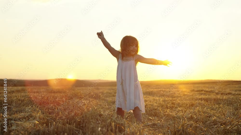 Happy smiling child throws straw up at sunset in the field. Growing wheat in the fields is a sign of children's happiness and love. High quality 4k footage Happy smiling child throws straw up at sunset in the field. Growing wheat in the fields is a sign of children's happiness and love. High quality 4k footage