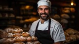 Portrait of a smiling male baker carrying fresh breads in a bakery.