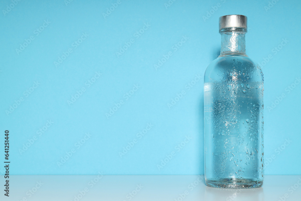 Glass bottle on blue background, space for text Glass bottle on blue background, space for text