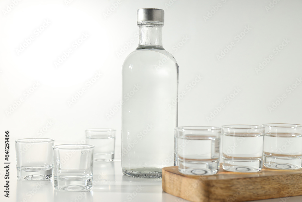 Glass bottle and glasses on wooden stand on white background Glass bottle and glasses on wooden stand on white background