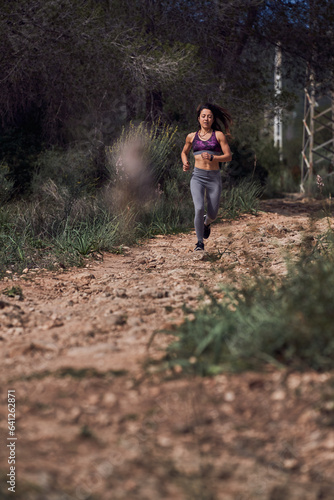 Serious athletic ethnic lady jogging on path in woods © ADDICTIVE STOCK CORE