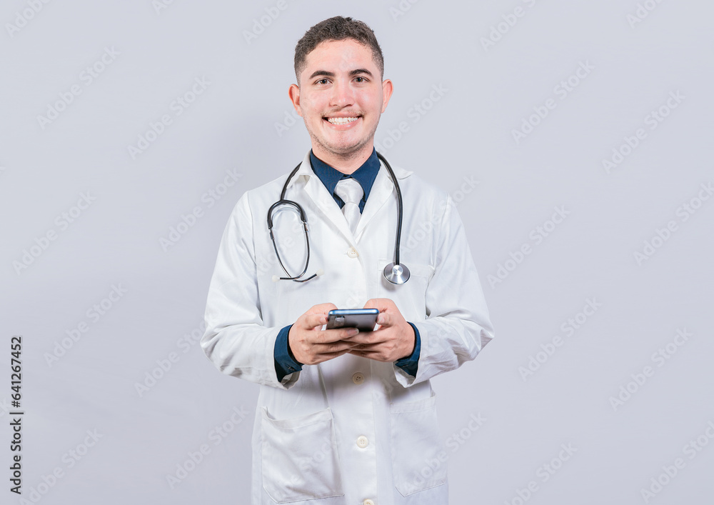Happy latin doctor holding phone isolated. Cheerful doctor using cellphone looking at camera isolated. Happy latin doctor holding phone isolated. Cheerful doctor using cellphone looking at camera isolated.