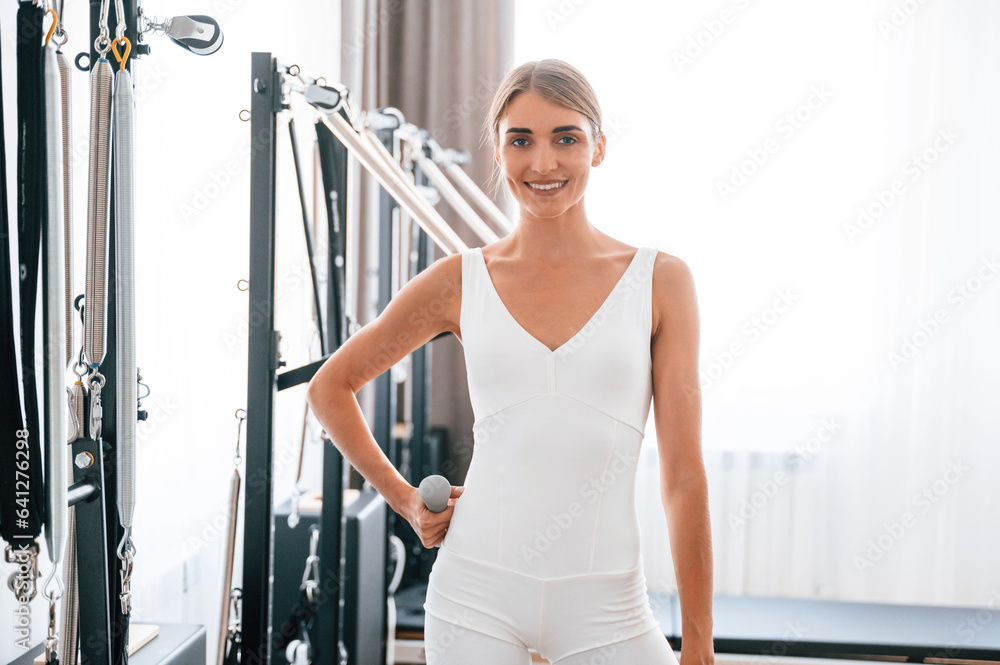 Standing and smiling. Young woman in fitness center is doing exercises Standing and smiling. Young woman in fitness center is doing exercises