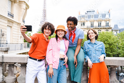 Group of young happy friends visiting Paris and Eiffel Tower - Multiethnic teens bonding outdoors and having fun sightseeing the city © oneinchpunch