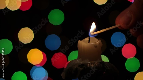 Lighting and burning candles in the dark, close-up against the background of multi-colored spots
