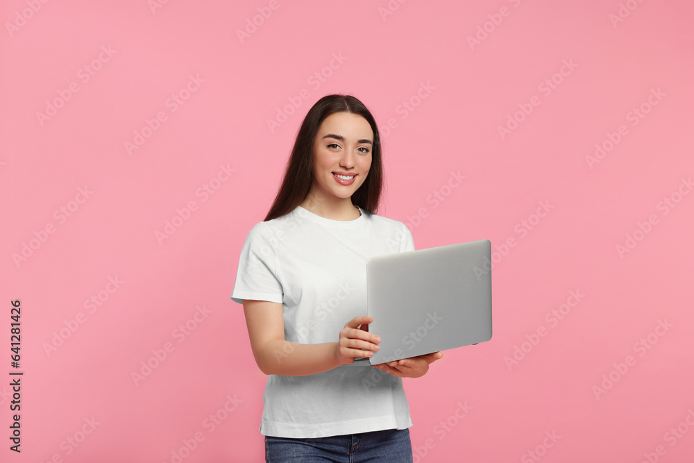 Smiling young woman with laptop on pink background Smiling young woman with laptop on pink background