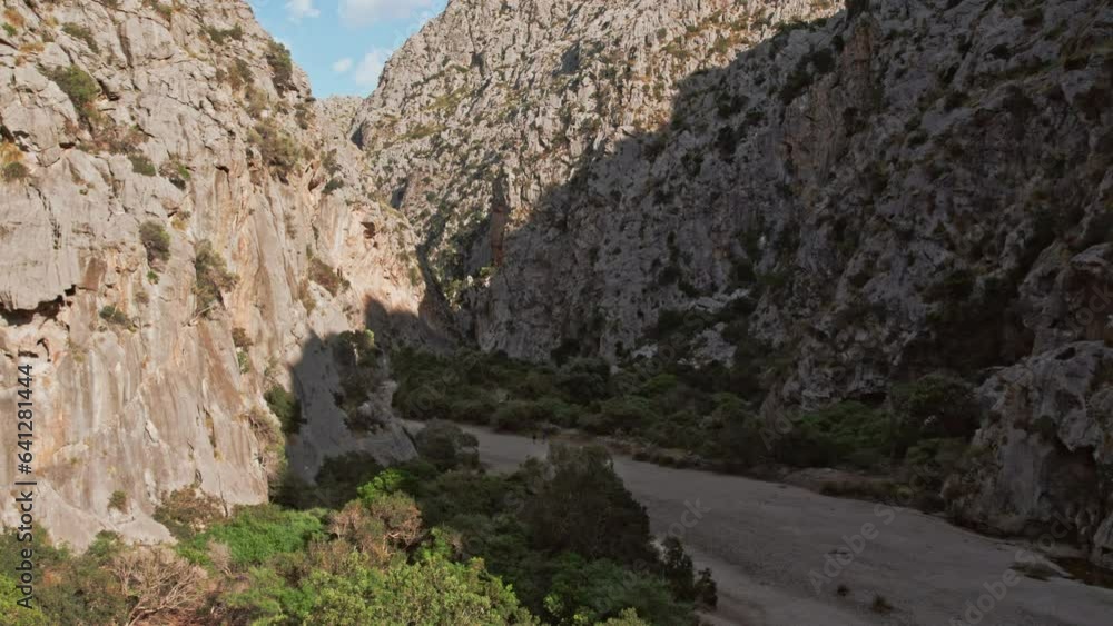 Tourists Trekking On Dry Riverbed Of Torrent de Pareis In Mallorca, Spain During Summer. aerial Tourists Trekking On Dry Riverbed Of Torrent de Pareis In Mallorca, Spain During Summer. aerial