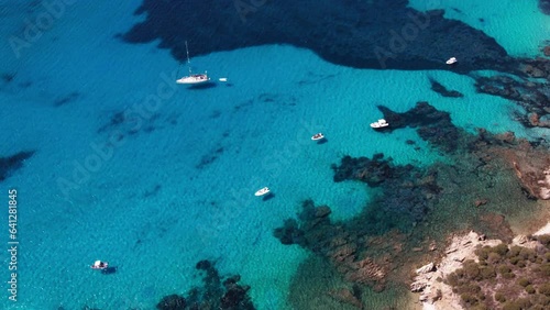 Boats stand near the shore with clear clear water on the island of Sardinia in Italy. Perfectly clear sea with clear water