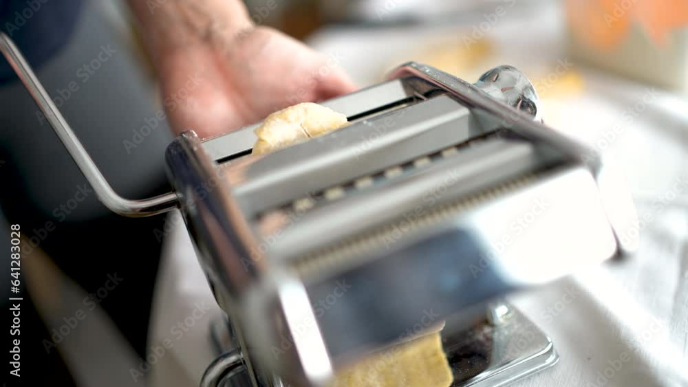 Woman rolls out the dough using a pasta dough rolling machine. Woman rolls out the dough using a pasta dough rolling machine.