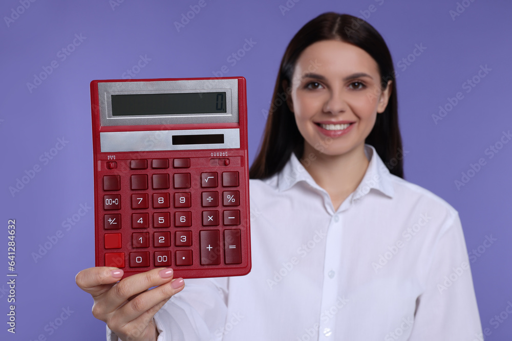 Smiling accountant against purple background, focus on calculator Smiling accountant against purple background, focus on calculator
